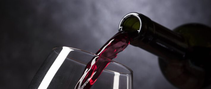 Rotwein fliesst in ein edles Weinglass