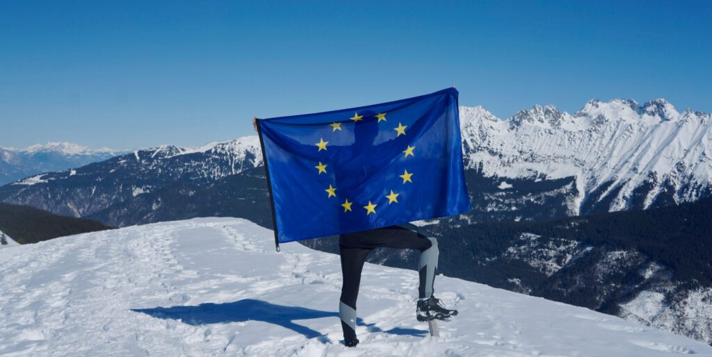 Eine Person mit einer EU-Flagge in den Bergen