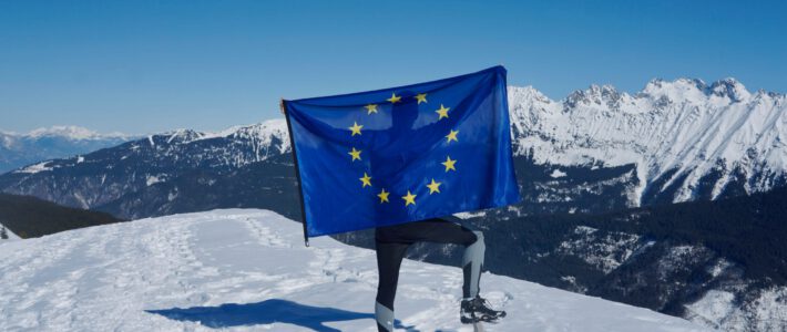 Eine Person mit einer EU-Flagge in den Bergen