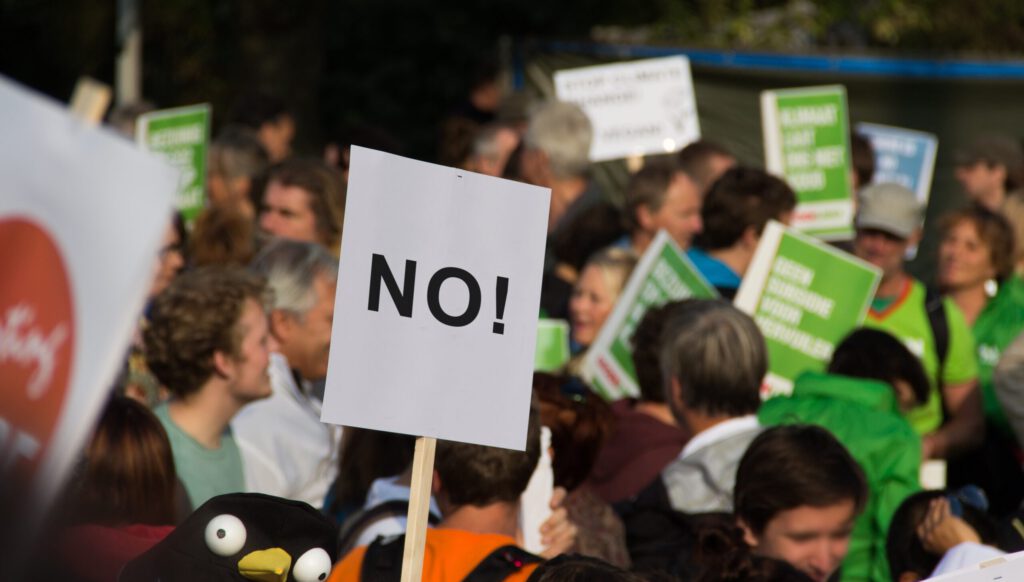 Menschen an einer Demonstration mit einem Schild «No»