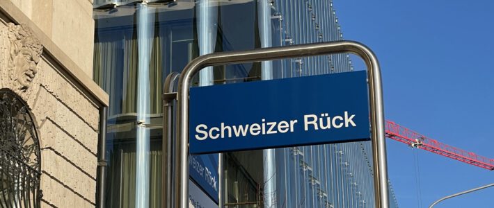 Schild an einer Bushaltestelle vor dem Gebäude des Rückversicherers Swiss Re in Zürich