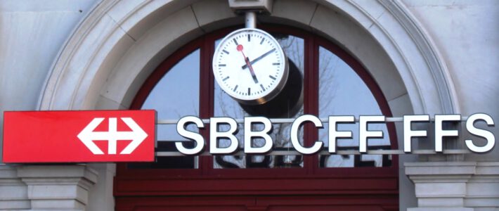 Blick auf einen Bahnhof in der Schweiz mit Bahnhofsuhr und SBB-Logo