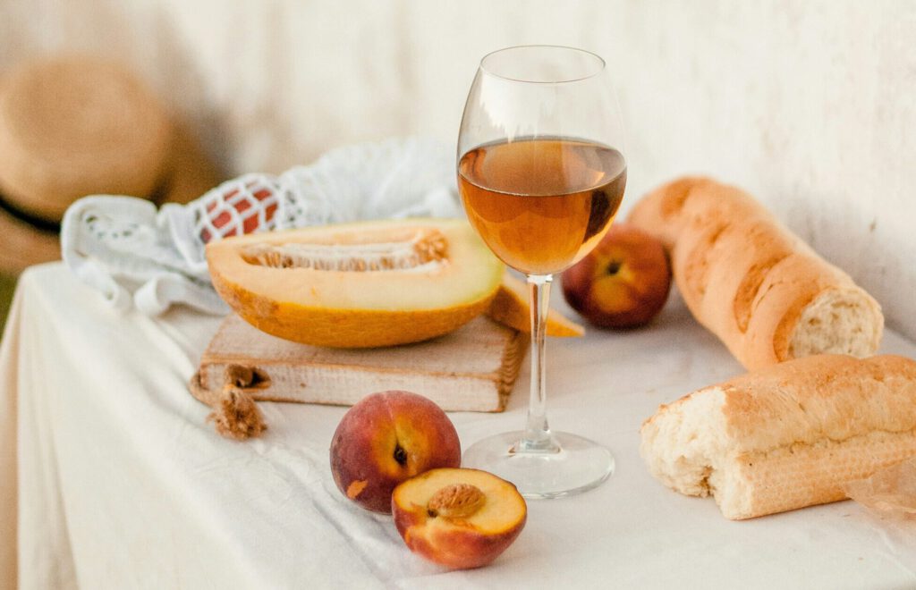 Ein Glas Wein mit Früchten und Brot auf einem Tisch