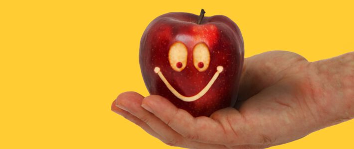 ein Apfel auf einer Hand mit einem lachenden Gesicht