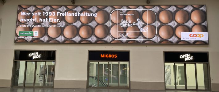 Migros in Basel mit Werbebanner von Coop