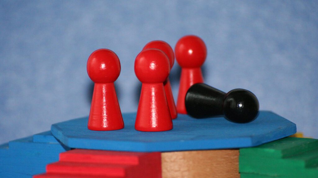 Rote Spielfiguren und eine schwarze Spielfigur auf einem Podest