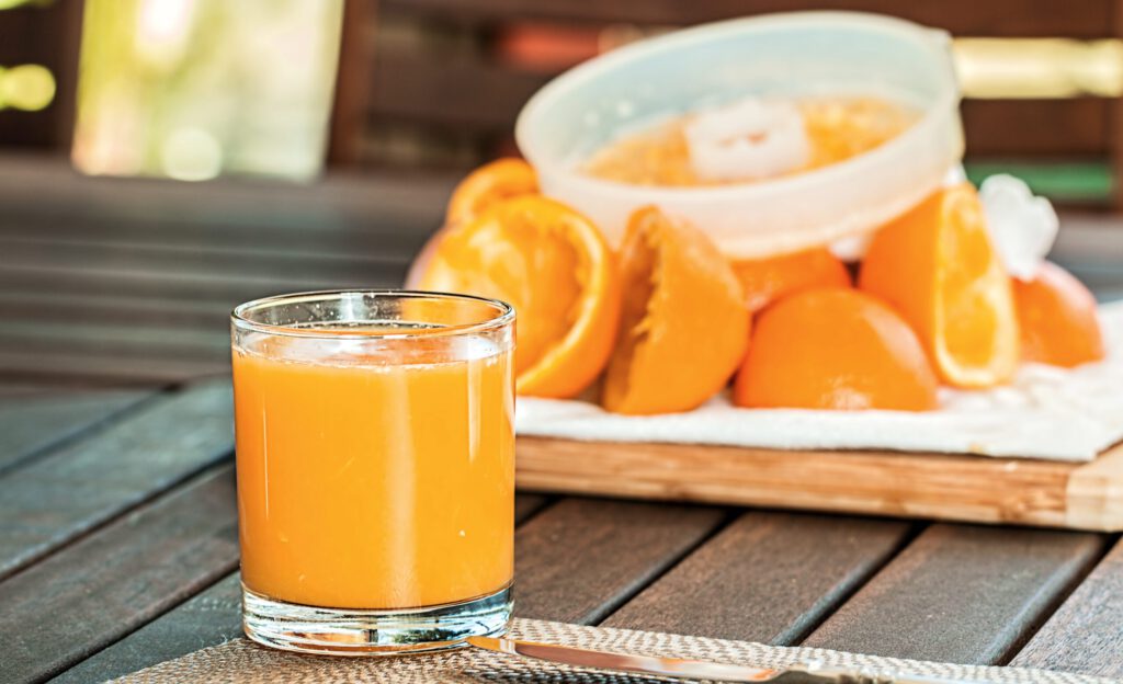 Ein Glas Orangensaft vor ausgepressten Orangenhälften