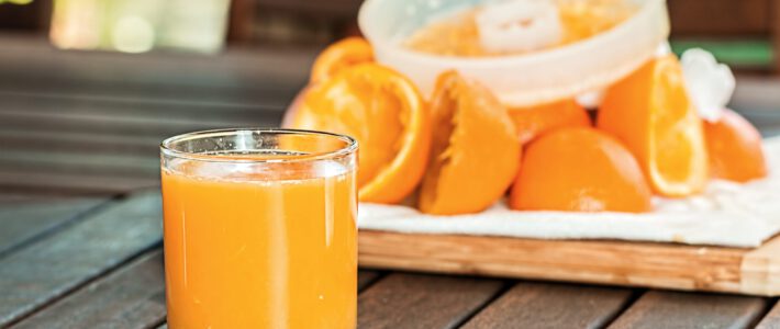 Ein Glas Orangensaft vor ausgepressten Orangenhälften