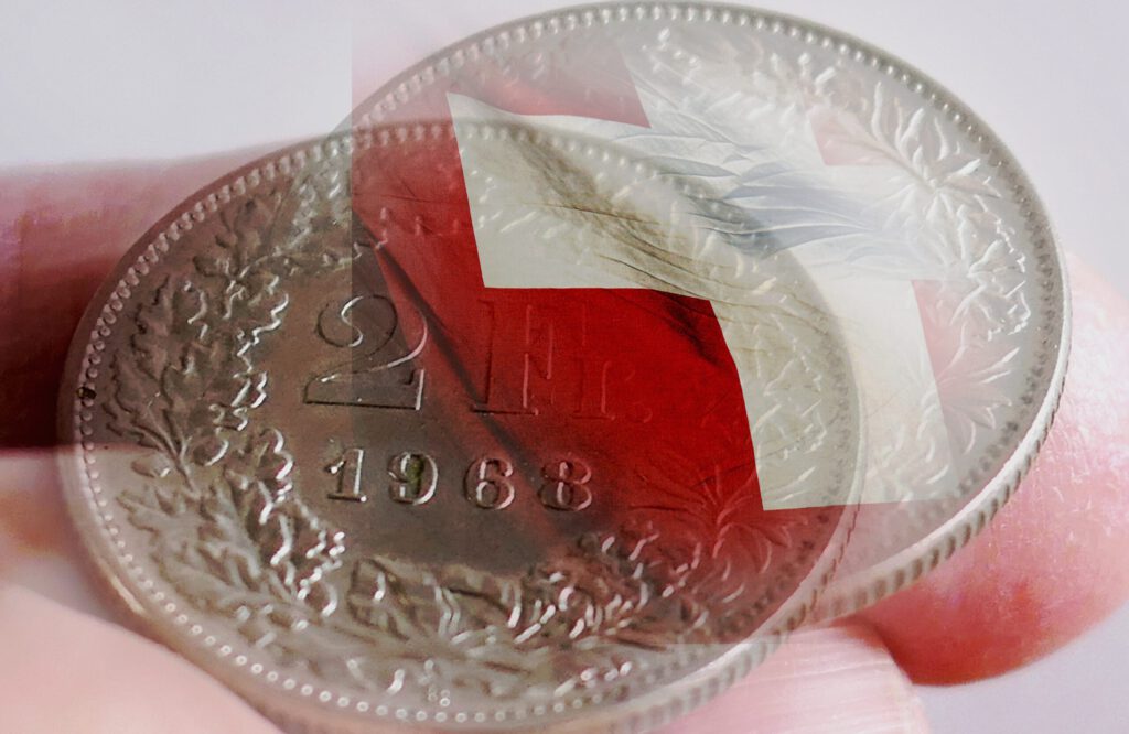 Eine Zwei-Franken-Münze mit einem Schweizerkreuz auf Fingern