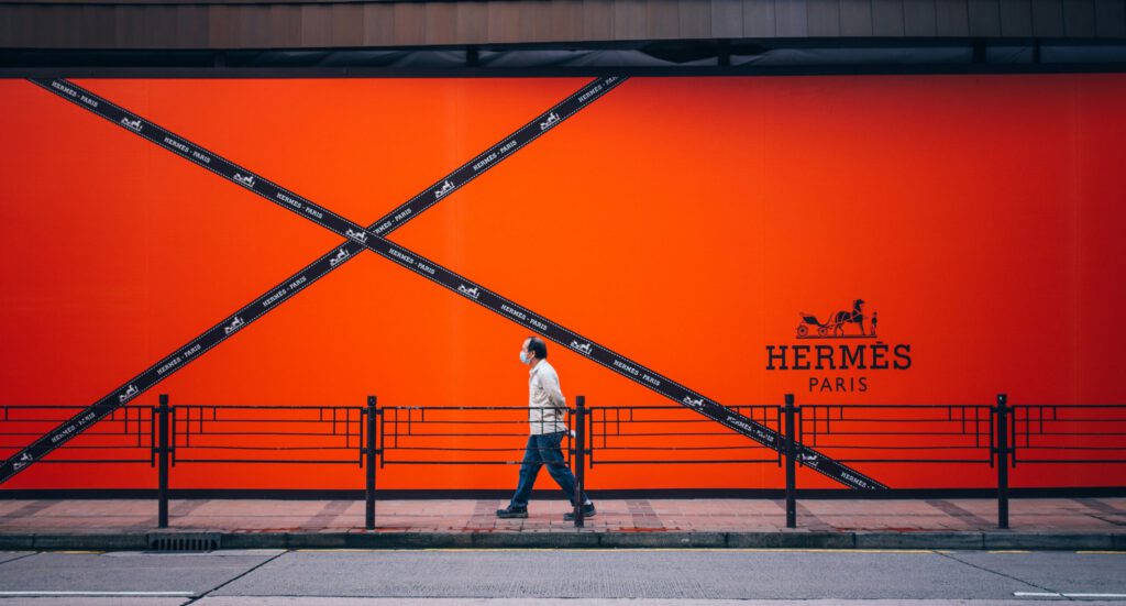 A person walking in front of an ad of Hermès