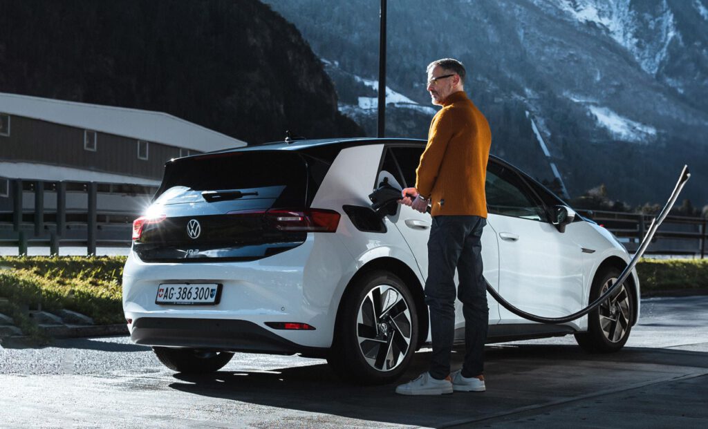 Ein Mann mit einem Elektroauto an einer Ladestation