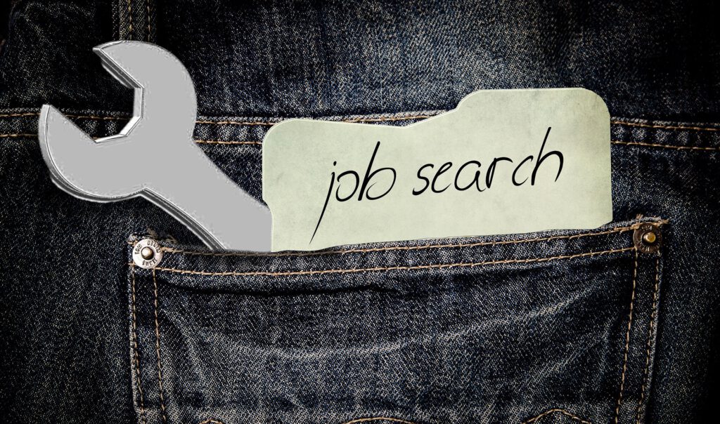 Hosentasche einer Jeans mit Schraubenschlüssel und Zettel «Job Search»