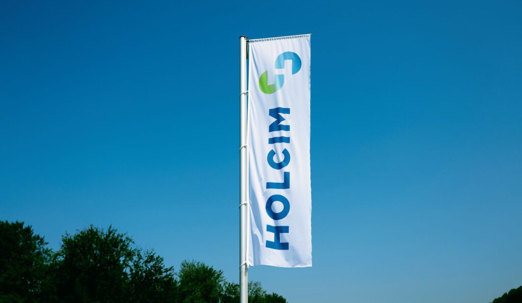 Eine Fahne mit Holcim-Logo vor blauem Himmel