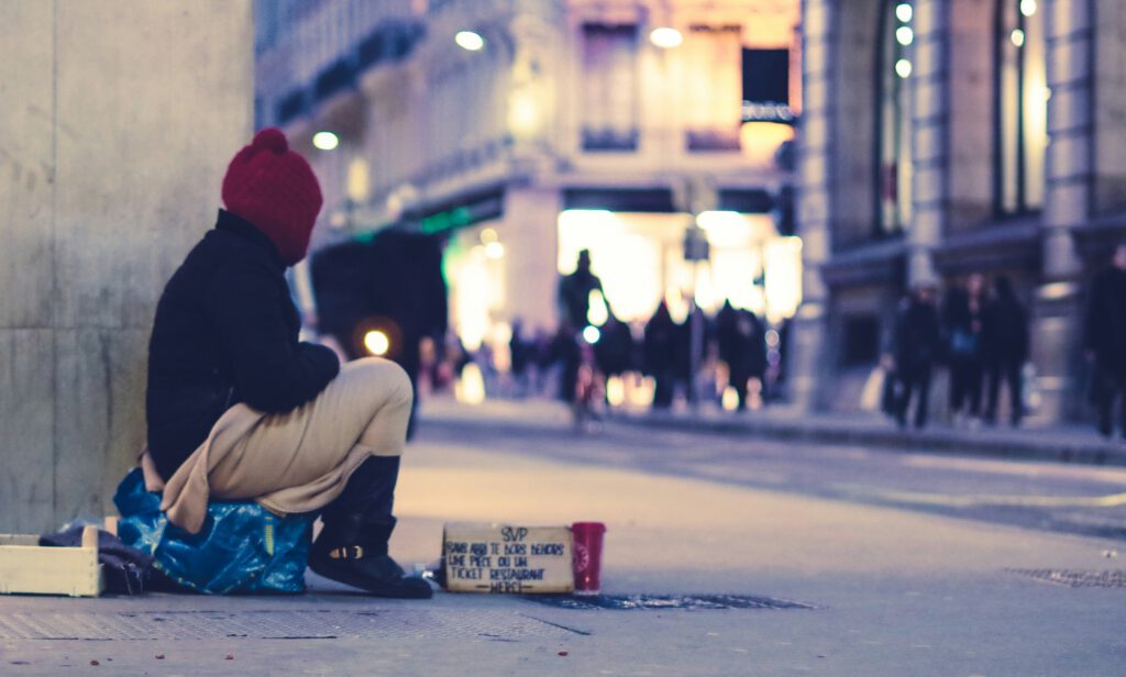 Ein Mann sitzt auf der Strasse und bittet um Geld