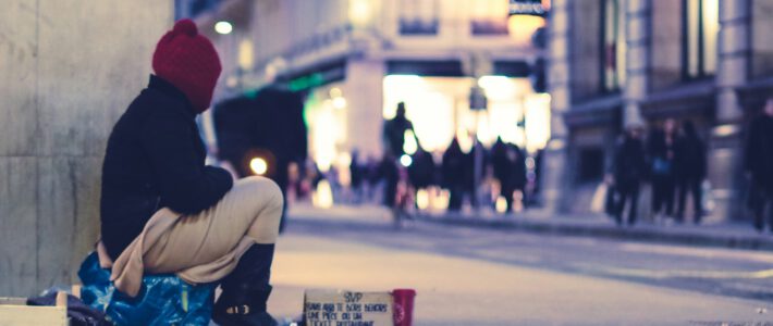 Ein Mann sitzt auf der Strasse und bittet um Geld