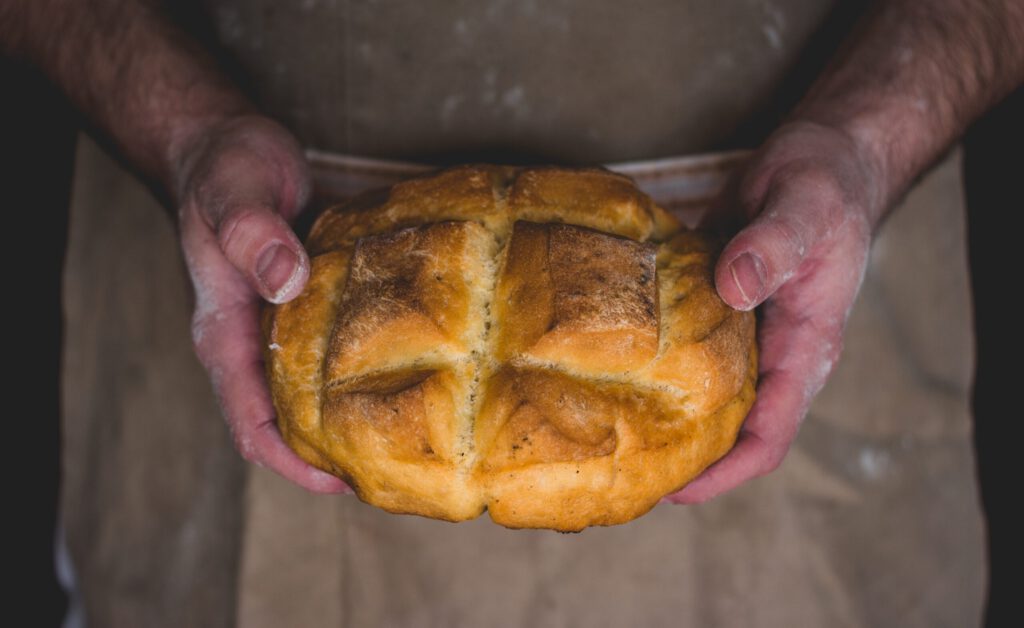 Ein Brot in den Händen eines Bäckers