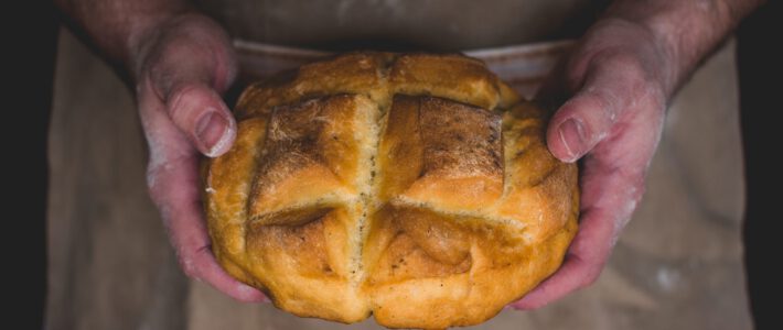 Ein Brot in den Händen eines Bäckers