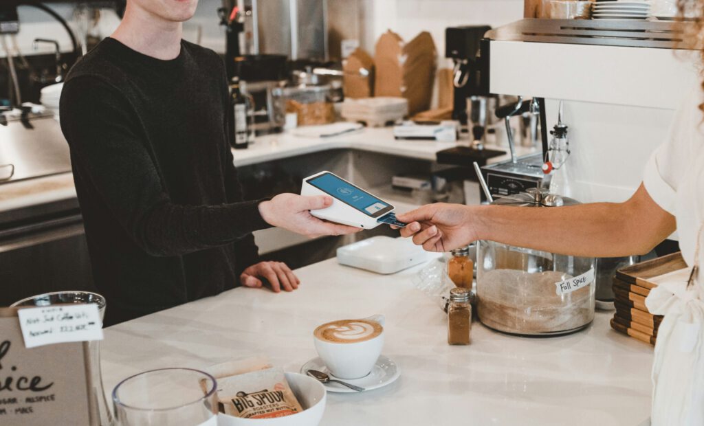 Ein Kunde zahlt einen Kaffee mit Karte in einem Café