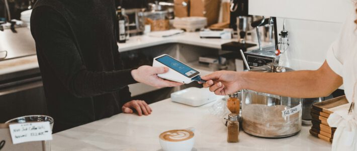 Ein Kunde zahlt einen Kaffee mit Karte in einem Café