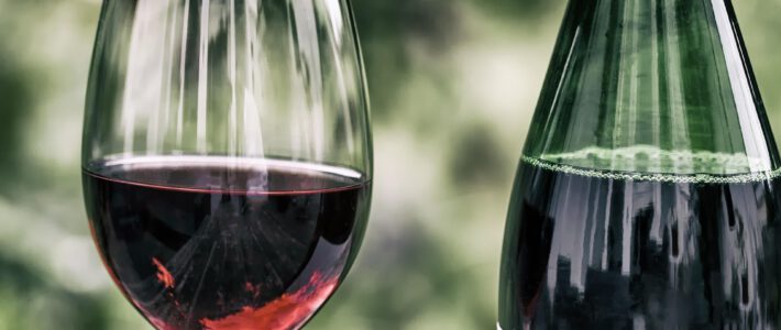 Schweiz will den Wein-Sozialismus ausbauen Ein Glas mit Rotwein und eine Weinflasche