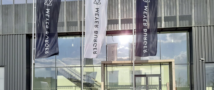 Fahnen mit Firmenlogo von Meyer Burger vor einem Firmengebäude