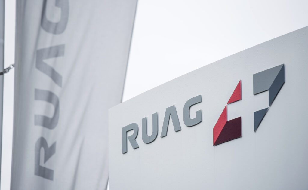 Logo und Schriftzug der Ruag an einer Fahne und einem Schild