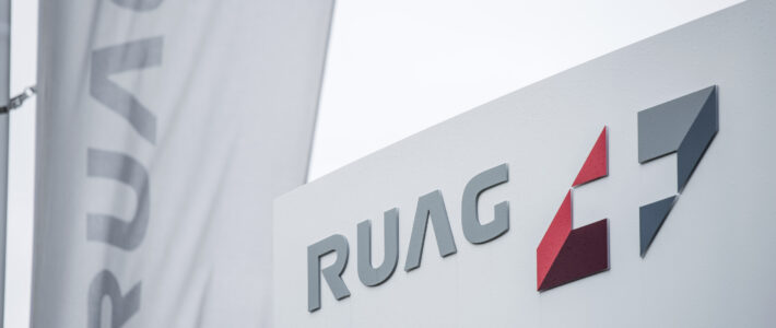 Logo und Schriftzug der Ruag an einer Fahne und einem Schild