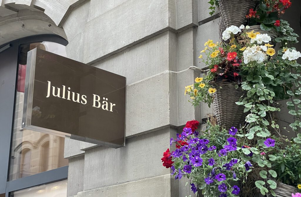 Logo von Julius Bär an einer Filiale mit Blumen