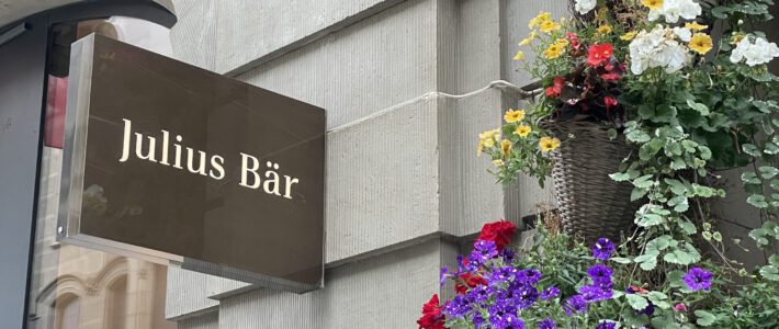 Logo von Julius Bär an einer Filiale mit Blumen