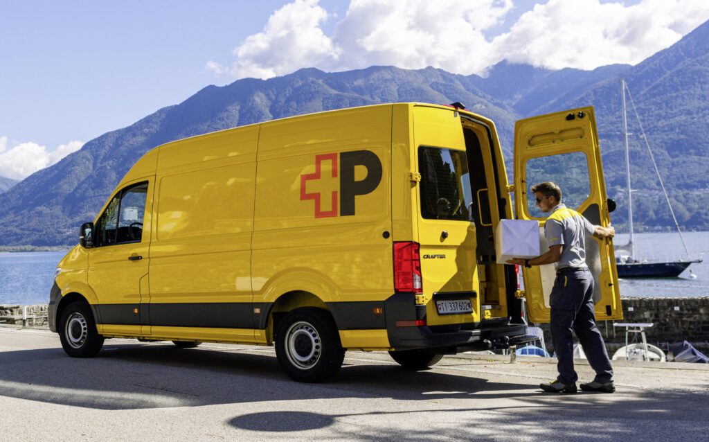 Ein Postzusteller mit neuer Kleidung und neuem Logo am Fahrzeug