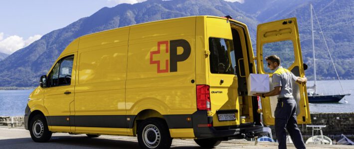 Neue Pöstler-Kleidung belastet die Post Ein Postzusteller mit neuer Kleidung und neuem Logo am Fahrzeug