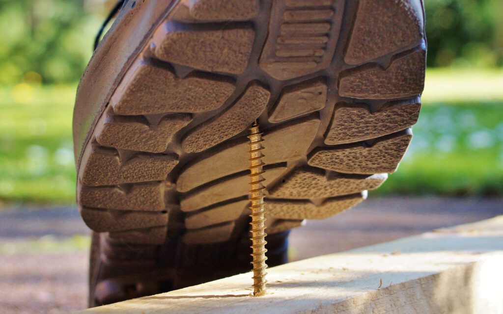 Ein langer Nagel bohrt sich in eine Schuhsohle