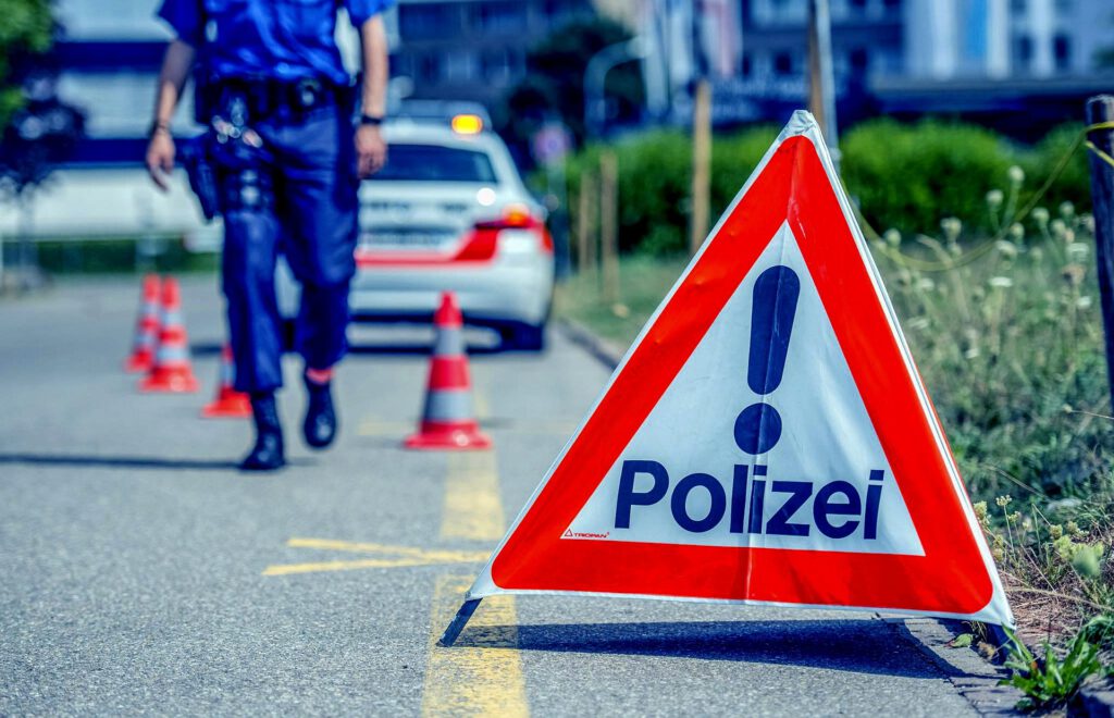 Ein Polizei-Schild sowie ein Polizeifahrzeug auf einer Strasse