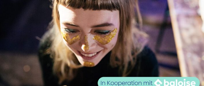 Eine Frau mit Goldfarbe im Gesicht und an einer Hand