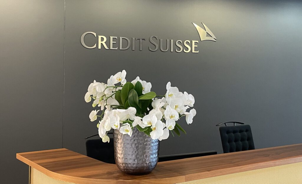 Logo der Credit Suisse an einer Rezeption mit Blumen