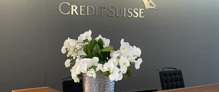 Logo der Credit Suisse an einer Rezeption mit Blumen
