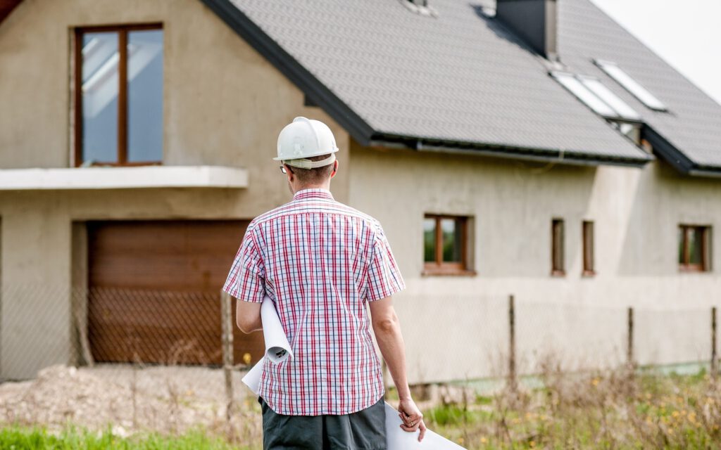 Ein Bauarbeiter vor einem Einfamilienhaus