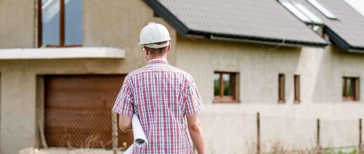 Ein Bauarbeiter vor einem Einfamilienhaus