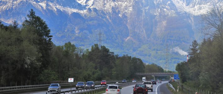 Schweizer zieht es auf die Strassen Eine Strasse mit Autos umgeben von Bergen