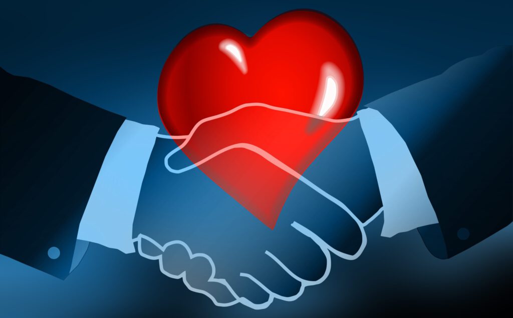 Zwei Hände mit Handschlag und ein rotes Herz