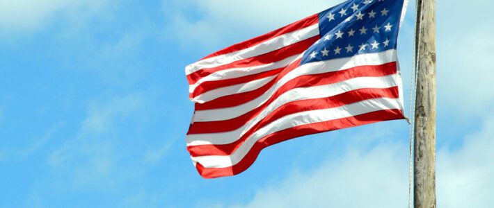 USA als Fels in der Brandung Eine US-Flagge im Wind an einem Holzmast