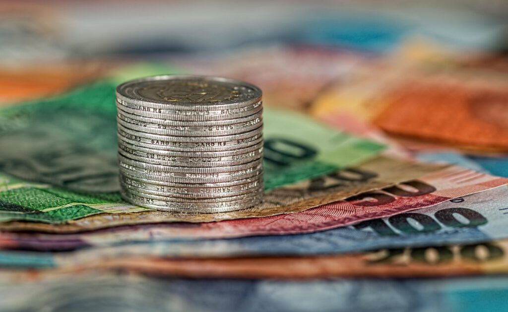 Bunte Geldscheine und ein Stapel an Münzen