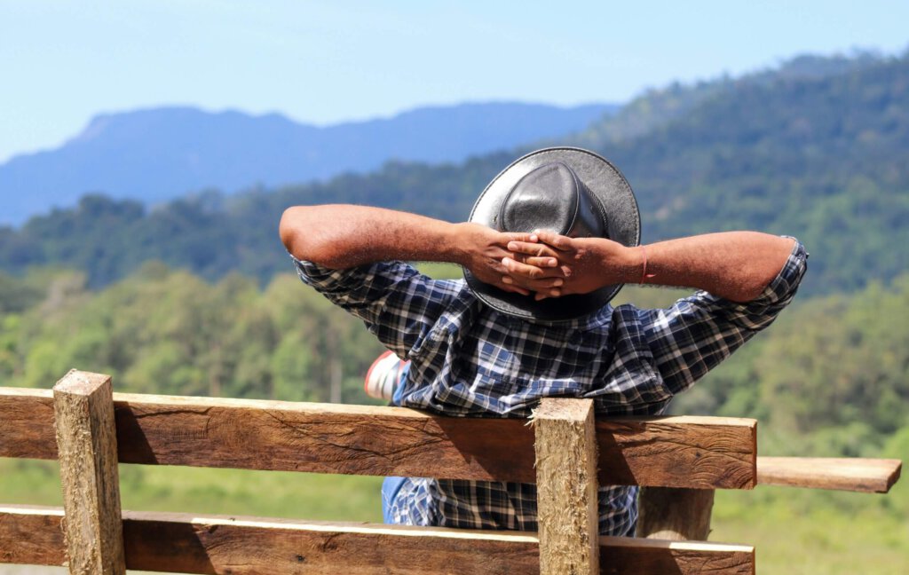Ein Mann geniesst die Landschaft von einer Bank mit verschränkten Armen hinter dem Kopf