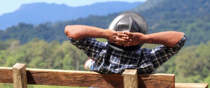 Ode an den Genuss Ein Mann geniesst die Landschaft von einer Bank mit verschränkten Armen hinter dem Kopf