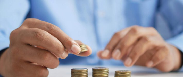 Kluge Geldentscheide zum Jahreswechsel Ein Mann in einem blauen Hemd legt Münzen auf verschiedene Stapel