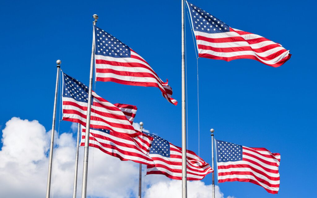 US-Flaggen im Wind vor einem blauen Himmel und Wolken
