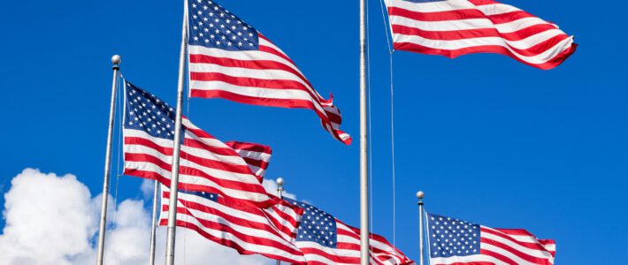 Boom der US-Wirtschaft US-Flaggen im Wind vor einem blauen Himmel und Wolken