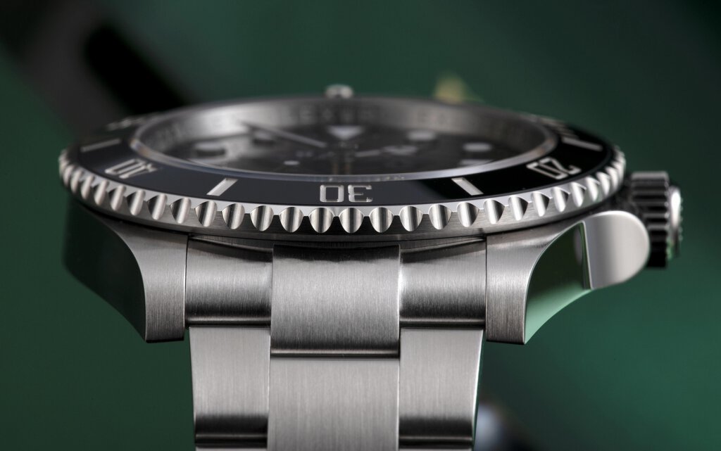 eine Rolex von der Seite vor grünem Hintergrund