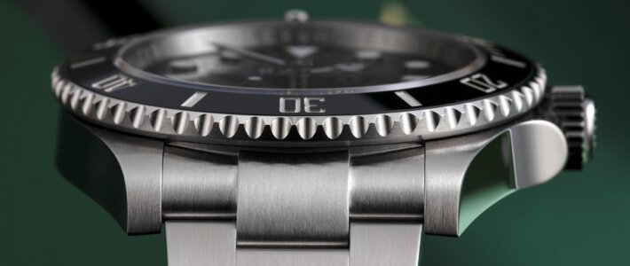 eine Rolex von der Seite vor grünem Hintergrund