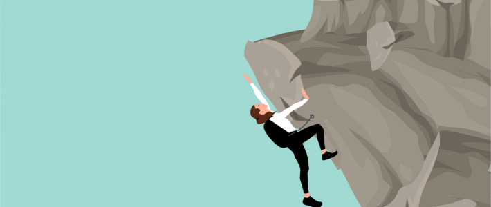 Eine Person hängt an einem Felsen und klettert nach oben